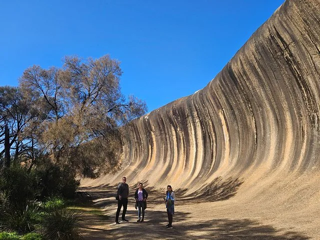Three people standing in front of the impressive curve of Wave Rock.