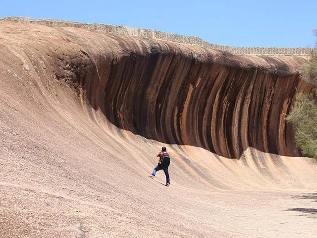 Eine Person steht nahe am Fuß des Wave Rock und macht Fotos.
