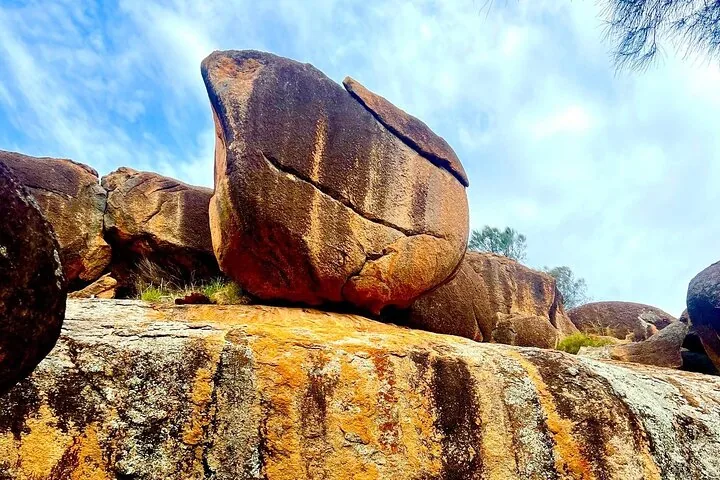 A large, unusually shaped boulder resting on top of a rocky outcrop.