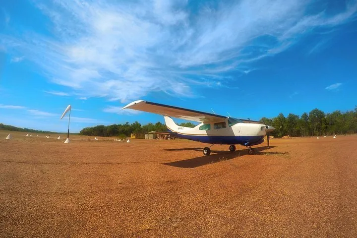 Ein kleines Flugzeug für Panoramaflüge steht auf einer roten Erdpiste.